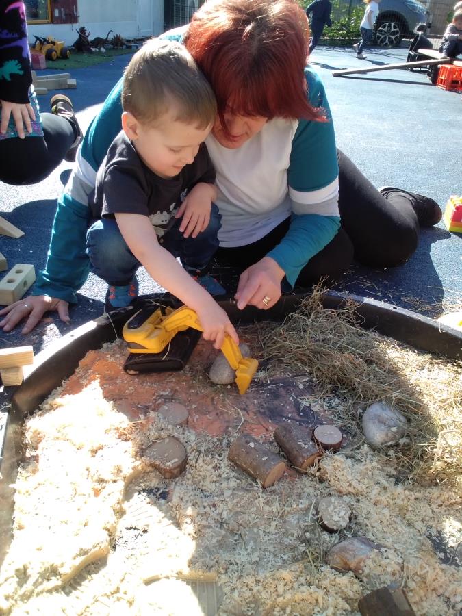 A child plays with a digger in a sandpit