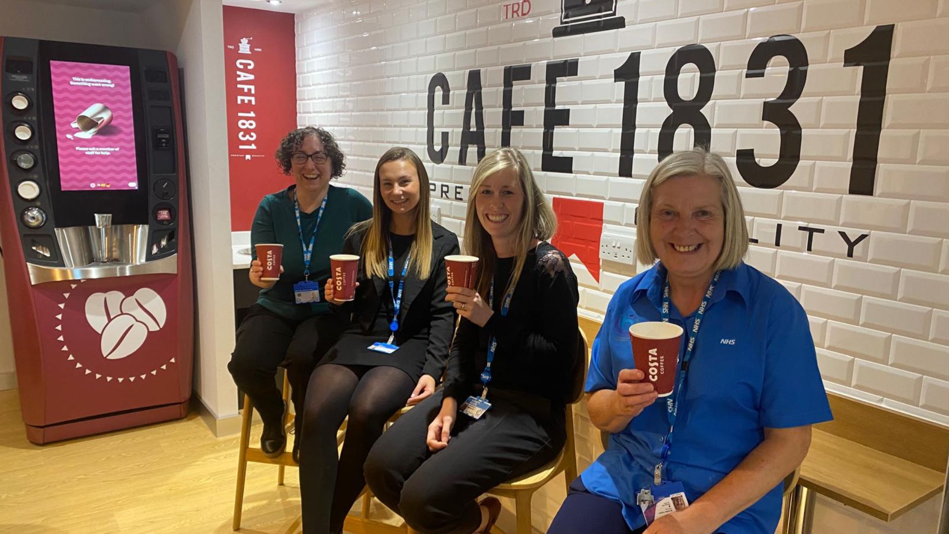 Members of staff posing with their coffee cups in the new café area at Acre Mills
