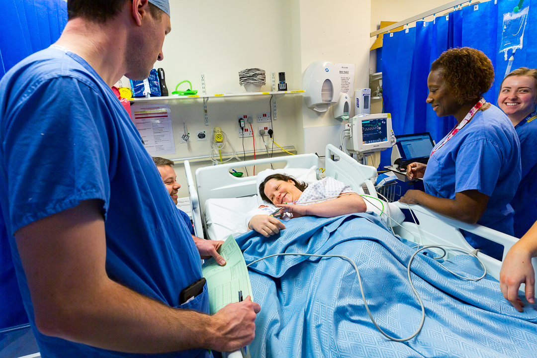 Doctors stood round patient in a bed 