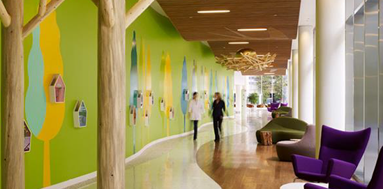 Two people stroll down a brightly coloured and wooden-themed corridor