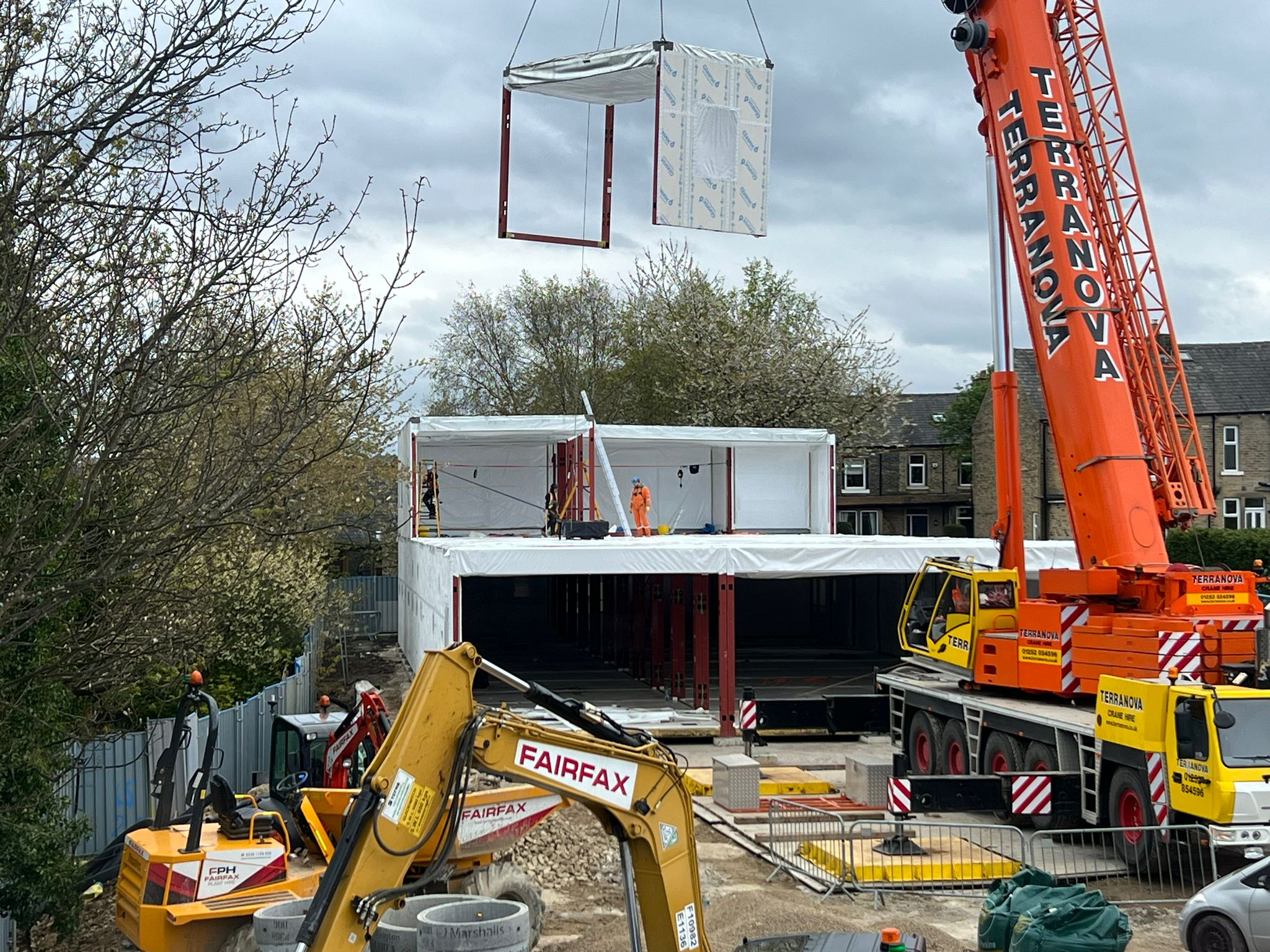The learning and development centre is assembled by a large orange crane lifting modules into position