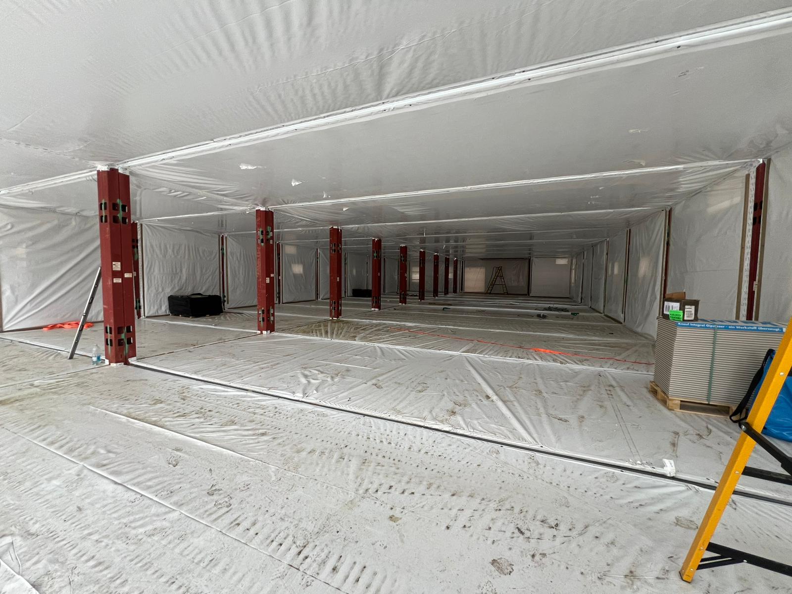The inside of the modular elements is currently covered by a white protective covering, with red beams  