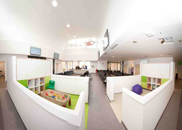 A small white wall surrounds the children's area, with a waiting area tucked behind it.