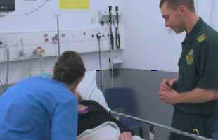 Clinical staff are caring for a patient who is lying in a bed bay.