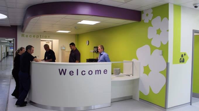 Staff dealing with patients at a colourful reception desk.
